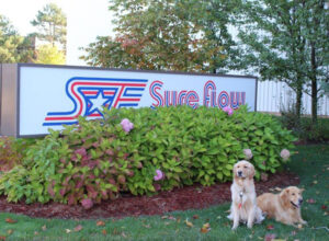 Odus and Acer in front of the Sure Flow sign